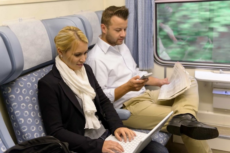 Пара едет в поезде, девушка с ноутбуком, парень с газетой. Они знают, что делать в поезде.