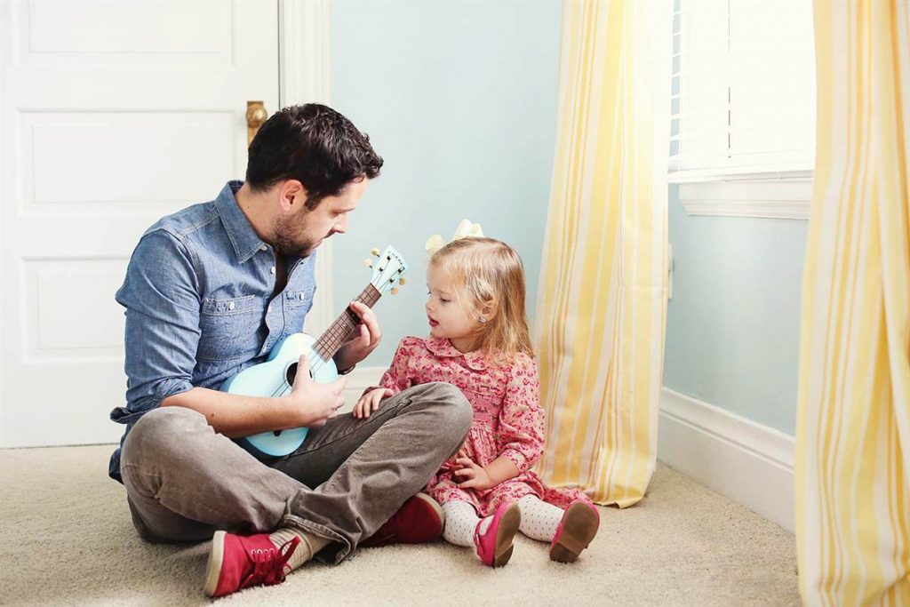 Папа играет дочке на гитаре.
