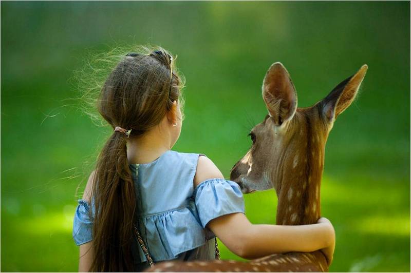 Девочка обнимает олененка.