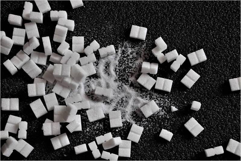 Белый сахар на черном фоне, применение сахара.
