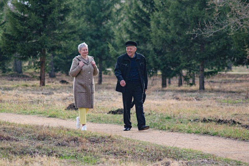 Пожилая пара гуляет по парку.