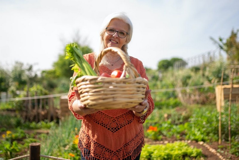Женщина с корзиной овощей, что растут на грядке.